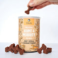 Load image into Gallery viewer, Hand holding a Gizzls Joint and Mobility dog treat above the tin