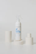 Load image into Gallery viewer, white dog perfume bottle in a clean white styled setting with blue writing 
